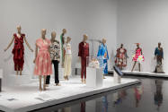 Art X Fashion exhibition installation view of ten dressed mannequins, a tablet and a bag in a c…