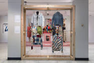 Beyond Utility exhibition installation view of four jackets hanging from a wooden frame with a …