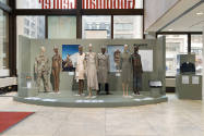 Beyond Utility exhibition installation view of seven dressed mannequins with a hat and a jacket…