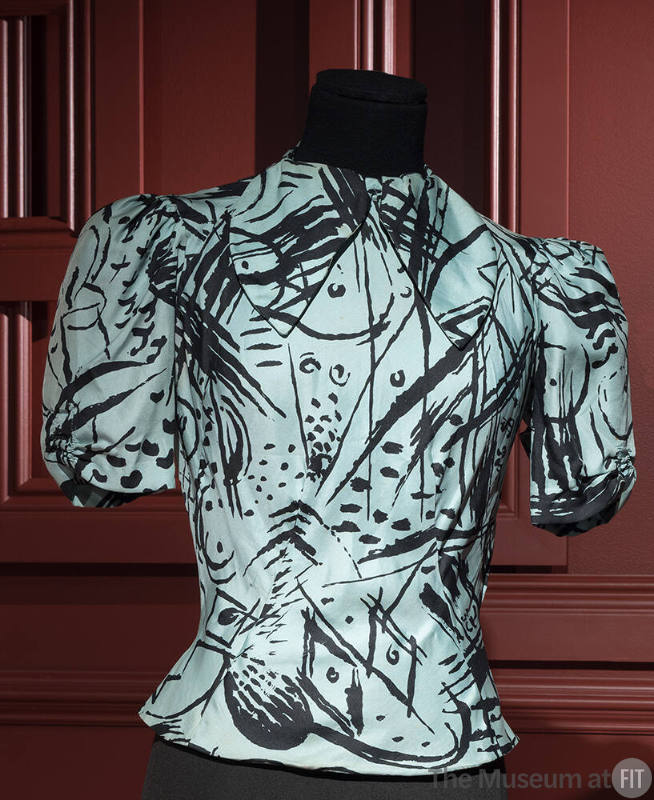 Turquoise blouse with black abstract pattern of lines and dots, band collar, short sleeves and …