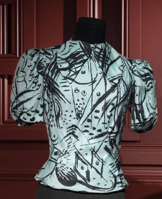 Turquoise blouse with black abstract pattern of lines and dots, band collar, short sleeves and …