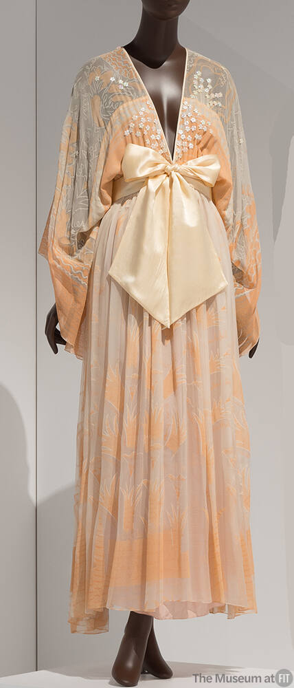 Off-white floor length gown with peach, orange and white floral print and deep V-neck meeting a…
