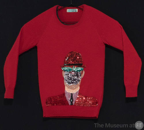 Red sweater with large center appliqué of a covered face wearing a hat in red, black, green, pu…