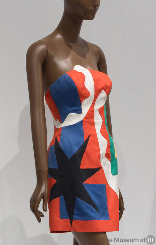 Strapless mini dress in pieced red, white, blue and green abstract shapes with large black star…