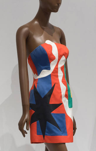 Strapless mini dress in pieced red, white, blue and green abstract shapes with large black star…