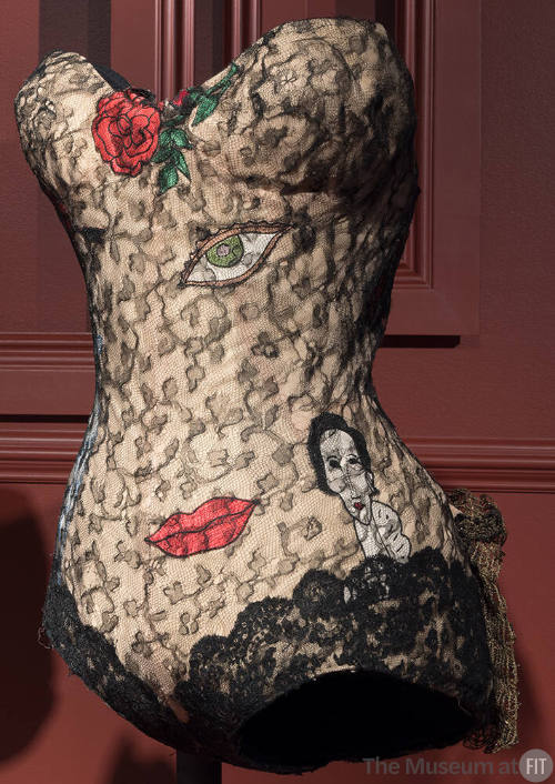 Beige strapless bodysuit with black lace overlay and surrealist appliqué motifs of a rose, eye,…