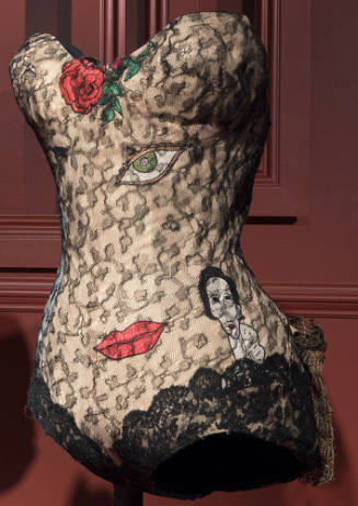 Beige strapless bodysuit with black lace overlay and surrealist appliqué motifs of a rose, eye,…