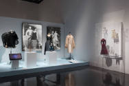 Doll Dressing exhibition installation view of three dressed mannequins and three dolls on a pla…