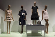 Doll Dressing exhibition installation view of four dressed mannequins and shoes, jewelry and a …