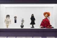 Doll Dressing exhibition installation view of a case with six dolls of various styles, sizes, s…