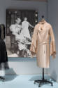 Doll Dressing exhibition installation view of an off-white negligee on a dress form in front of…