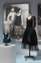 Doll Dressing exhibition installation view of black dress on a dress form, a doll in a case and…