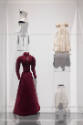 Doll Dressing exhibition installation view of a case with four miniature garments: stays, an in…