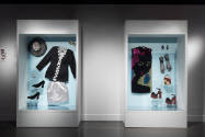 Doll Dressing exhibition installation view of two large cases containing clothing and accessori…