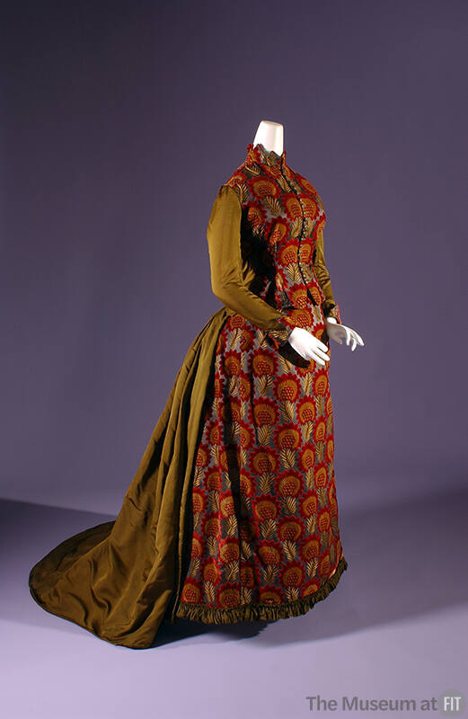 Floor length bustle dress in red and gold floral velvet with contrasting olive green silk sleev…