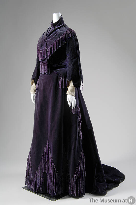 Deep purple gown with fringe and tassels, bell sleeves and floor length skirt with train