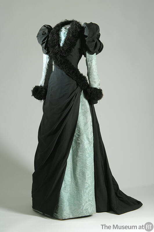 Floor length black dress with puffed sleeves, light green underdress and cross over bodice with…