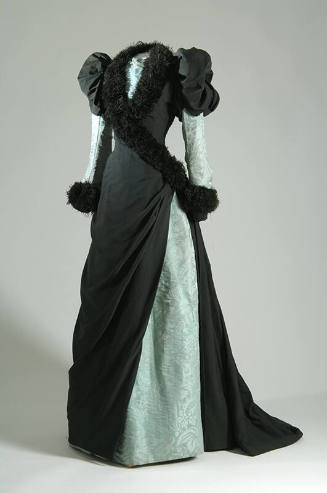 Floor length black dress with puffed sleeves, light green underdress and cross over bodice with…