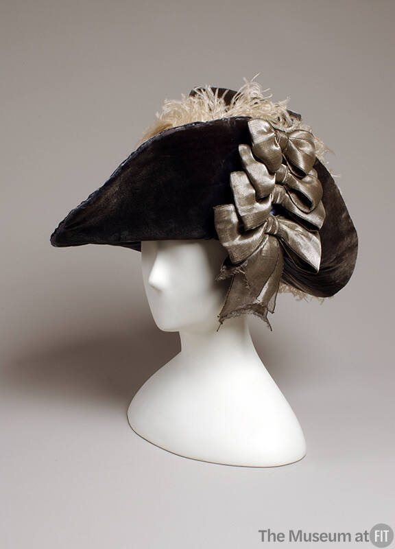 Blue velvet hat with four silver bows on right side and grey feathers in plume