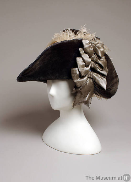 Blue velvet hat with four silver bows on right side and grey feathers in plume