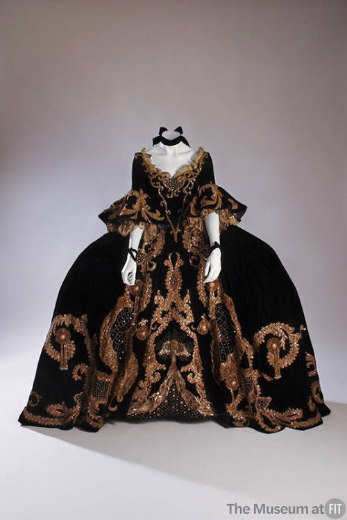 Black velvet two-piece dress with wide panniers decorated with gold scroll-like trimmings throu…