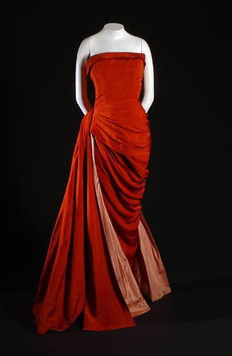 Red strapless floor length evening dress with a long drape across hip to reveal pink lining