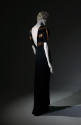 Back view of black floor-length evening dress with deep V-back and thick bronze stripes across …