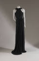 Black floor-length sleevless evening dress with halter neckline and skirt gathered and draped a…