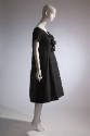 Black knee-length dress with wide sweetheart neck, bow, and short sleeves