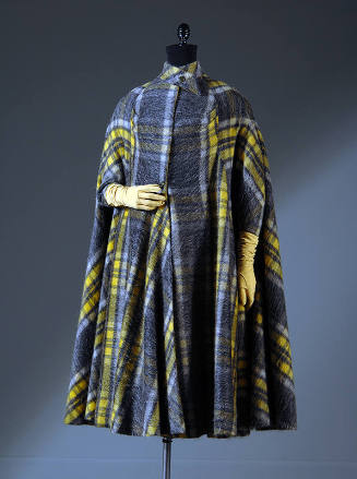 Cape coat of yellow and grey plaid with crossed and buttoned band collar and narrow sleeves