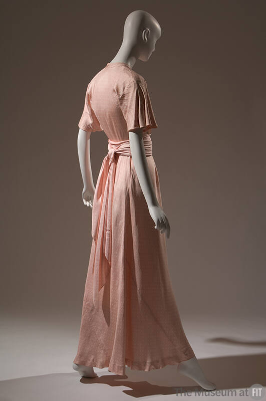 Back view of pink ankle length afternoon dress; short bell sleeves; sash tied at waist