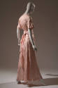 Back view of pink ankle length afternoon dress; short bell sleeves; sash tied at waist