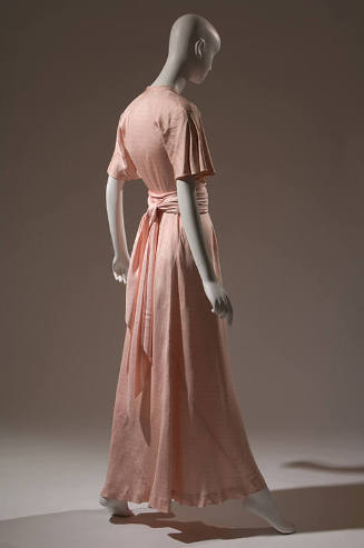 Back view of pink ankle length afternoon dress; short bell sleeves; sash tied at waist