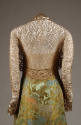 Back view of gold floral lace bolero worn over floral brocade dress