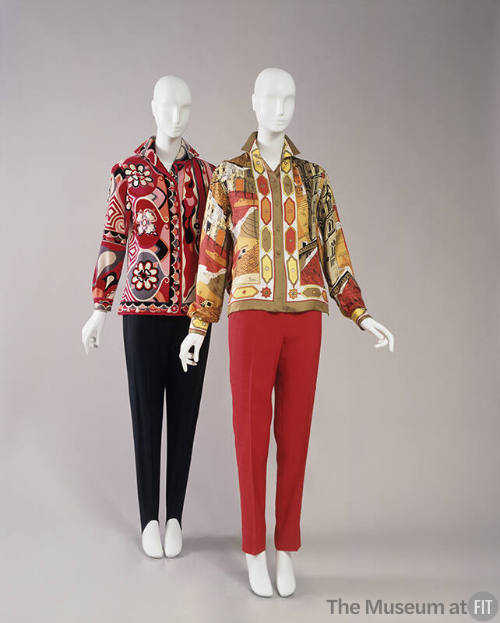Two mannequins wearing patterned button-up tops with tapered pants, one black, one red