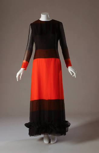 Black long sleeve floor length slip dress with large orange color block from hip to knees and a…