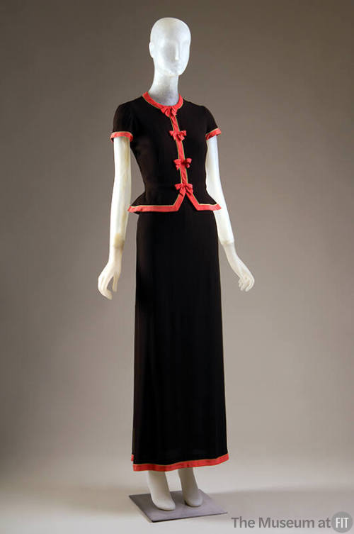 Black two-piece dress of short sleeve bodice and floor length straight skirt with coral trim do…