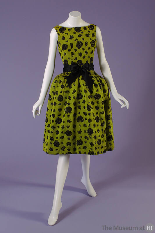 Green sleeveless evening dress with black rose pattern, black bow tied at waist and knee length…