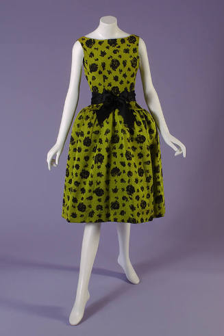 Green sleeveless evening dress with black rose pattern, black bow tied at waist and knee length…