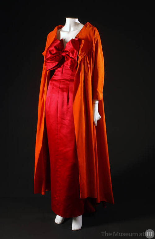 Red floor length evening dress with oversize bow at neck and long orange coat