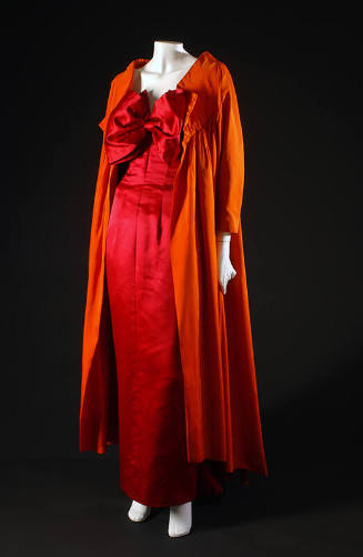 Red floor length evening dress with oversize bow at neck and long orange coat