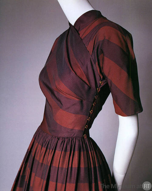 Detail view of red and purple striped dress showing bias cut bodice with high neck and brass ho…
