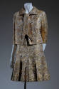 Gold lame and silk brocade evening suit with ties at neckline, ¾ sleeves and pleated mid thigh …