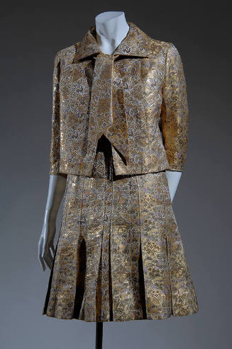 Gold lame and silk brocade evening suit with ties at neckline, ¾ sleeves and pleated mid thigh …