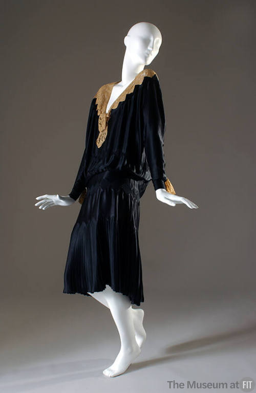 Black evening dress with lace neckline and wrist trim, pleated skirt