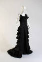 Sleeveless floor length black evening tress, draped bow at right shoulder, tiered flounce skirt