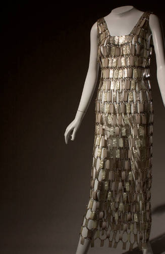 Long, sleeveless chain mail dress of pearlescent and silver plastic rectangles linked by metal …