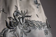 Detail of metallic thread embroidery of flowers on pale ice blue dress