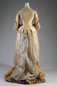 Back view of cream two piece dress, pleated side panels, long skirt with train