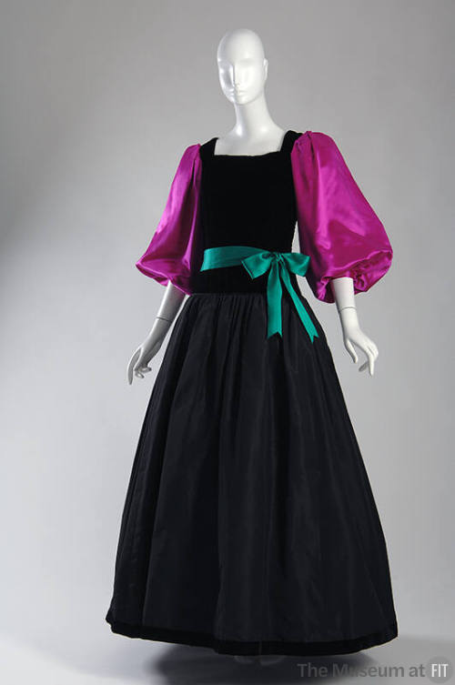 Black floor length gown with square neck, full skirt, fuchsia balloon sleeves and green tie bel…